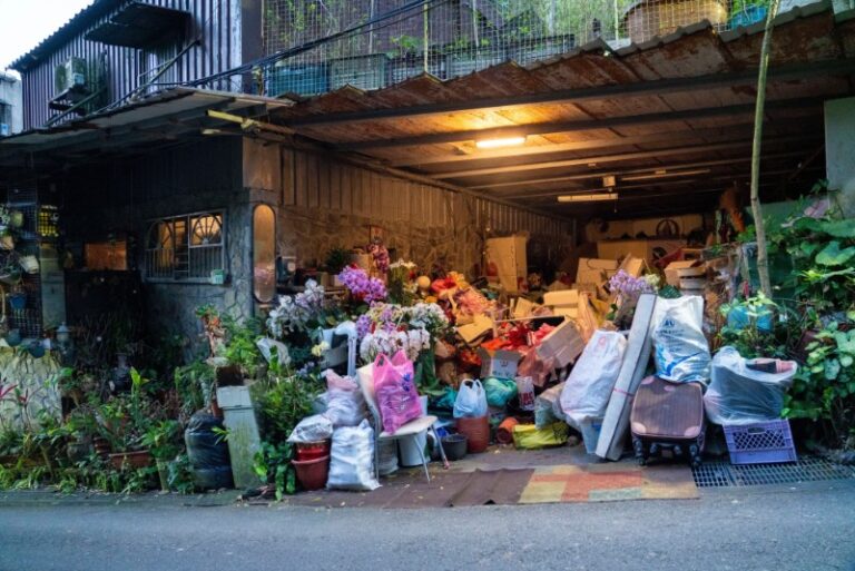 A cluttered garage in Hemet, California, packed with boxes, old furniture, and household junk before a professional cleanout.